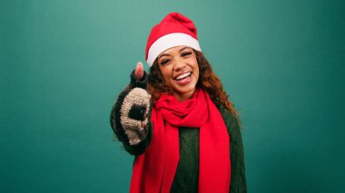 Gülümseyen, etnik çeşitlilikte genç bir kadın Noel Baba şapkasını stüdyoda onaylıyor. Yüksek kalite fotoğraf