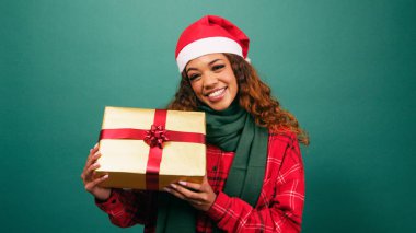 Güzel genç bir bayan Noel hediyesini elinde tutuyor, Noel Baba şapkası stüdyosunda gülümsüyor. Yüksek kalite fotoğraf