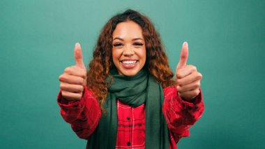 Gülümseyen çok ırklı genç bir kadın stüdyoda, Noel 'de çifte onay veriyor. Yüksek kalite fotoğraf