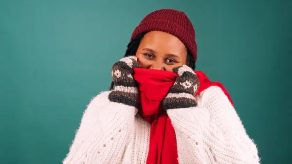Freezing cold woman bundles up against the cold, huddles in warm scarf, studio. High quality photo