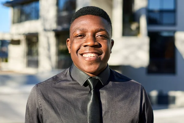 Portrait of young Black businessman smiling, wearing black shirt and tie. High quality photo