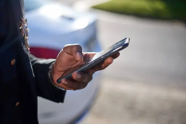 Cropped image of Black business man holding cellphone while outside. High quality photo