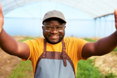 Siyahi çiftçi arka planda serayla selfie çekiyor, gülümsüyor. Yüksek kalite fotoğraf