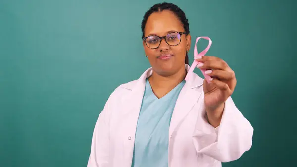 stock image Black female doctor holding pink breast cancer awareness ribbon, serious face. High quality 4k footage