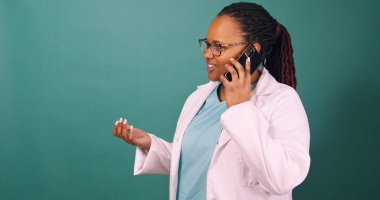 Meşgul siyah kadın doktor cep telefonlarına cevap veriyor, fotokopi çekmekten bahsederken el kol hareketleri yapıyor. Yüksek kalite fotoğraf