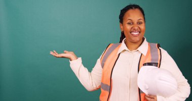 Siyah inşaat işçisi, elinde şapkayla gülümsüyor, inşaat mimarı üzerinde çalışıyor. Yüksek kalite 4k görüntü