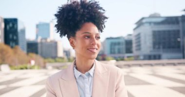 Afro gülüşlü genç siyahi bir kadın şehir merkezine doğru bakıyor. O mutlu ve kendinden emin. Profesyonel iş kıyafeti giyiyor..