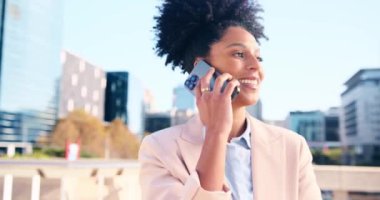 Arka planda şehir binalarıyla cep telefonuyla konuşan ve gülümseyen, spor ceketli Afro-Amerikan iş kadınının portresi.