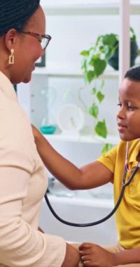 Pediyatri doktoru, genç hastasına sağlık kontrolü sırasında steteskop kullanmasına izin vererek neşeli ve olumlu bir sağlık deneyimi yaratıyor.