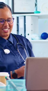 Mutlu ve dost canlısı doktor bilgisayarını kullanarak bir hastaya tele sağlık danışmanlığı sağlıyor.