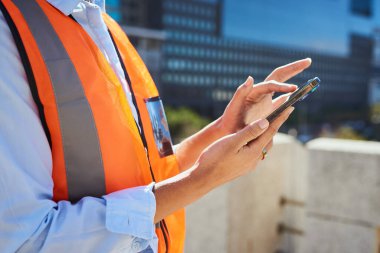 Şehir merkezinde akıllı telefon kullanan çelik yelek giyen inşaat işçisi. İnşaat teknolojisi ve modern endüstriyel işlemler kavramı.