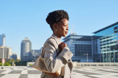 Şık bir kadın modern bir şehir ortamında zarif kıyafetlerini ve duruşunu sergileyerek rahatça dolaşır.. 