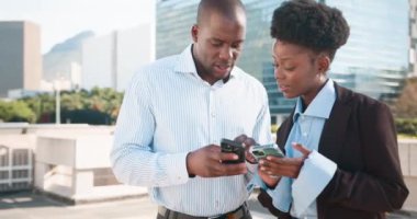 İki Afrikalı iş arkadaşı modern bir şehirde tartışıyorlar. İkisi de resmi giyinmiş ve gülümsüyor. Akıllı telefonlarıyla bir şeyler konuşuyorlar.. 