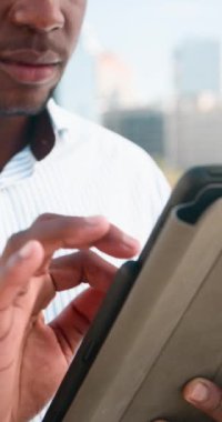 Şehir ortamında tablet kullanan bir iş adamına yaklaş. Çizgili bir gömlek giyiyor. Bu video modern çağda profesyonelliği, teknolojiyi ve ticareti çağrıştırıyor..