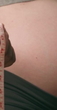 Hamile kadın göbeğini ölçüyor. Hamile bir kadın bebeğinin şişkinliğinin boyutunu ölçer. Annelik, hamilelik, sağlık ve annelik kavramları. Hamile karnına yakın plan..