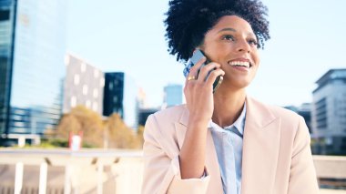 Kendine güvenen bir iş kadını telefonda konuşurken gülümsüyor, modern bir ofis bölgesinde dışarıda duruyor. Pozitif ve profesyonel kentsel ortam.