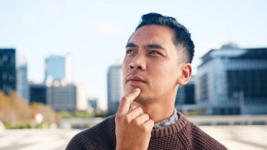 Elleri çenesinde düşünceli bir adam gün ışığında şehir planında derin düşüncelere dalmış..