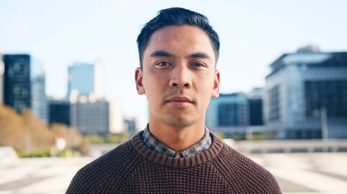 Ofis binaları ve şehir manzarası arka planda görünen, dışarıda duran genç bir adamın yakın plan portresi..