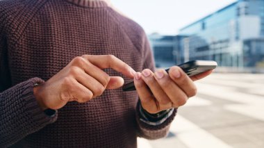 Şehir ortamında açık havada akıllı telefon kullanan birinin yakın plan görüntüsü. Eller, teknoloji ve modern iletişim üzerine odaklanın..