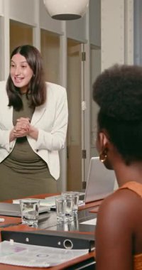 Ofiste bir toplantıda iki farklı iş kadını gülüyor ve ellerini çırpıyor. Büyük bir anlaşma yaptılar ve sonuçlardan memnunlar. Alkışlar, ofis, kadınlar, iş, başarı.