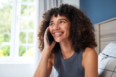 Gülümseyen genç bir kadın evde otururken hoş bir telefon konuşması yapıyor. Oda aydınlık ve misafirperver, onun neşesini arttırıyor..