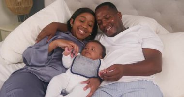 Mutlu bir aile yatakta birlikte zaman geçirmekten hoşlanır. Anne ve baba sevimli bebekleriyle sarılıp oynuyorlar. Bu iç açıcı sahne aile içindeki sevgi ve bağlantıyı yakalar..