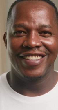 Mutlu bir Afrikalı Amerikalı adam kameraya gülümsüyor. Mutluluğu, aileyi, evi ve sevgiyi temsil ediyor. Bu görüntüler neşe ve memnuniyeti çağrıştırıyor. Aile değerlerini ve olumlu duyguları destekleyen projeler için ideal.