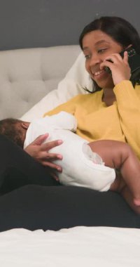 Mutlu bir Afrikalı Amerikalı anne yeni doğmuş bebeğini emzirirken yürek ısıtan bir anın tadını çıkarıyor. Çoklu görevleri zahmetsizce yerine getiriyor, küçük yavrusunu bir telefon görüşmesine katılırken yanında tutuyor, neşe ve memnuniyet saçıyor..