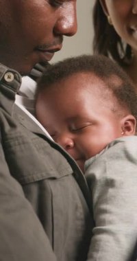 Sevgi dolu bir baba uyuyan bebeğini göğsüne yakın tutar. Bebek mışıl mışıl uyuyor ve huzur içinde gülümsüyor. Aile bağlarının ve sevginin iç açıcı bir sahnesi. Anne de orada ama kısmen gözden uzak, huzurlu anın tadını çıkarıyor..