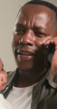 Mutlu bir baba, sevimli bebeğini kucağında tutarken neşeli bir gülümsemeyle bir telefon görüşmesi yapar. Modern ebeveynliğin iç açıcı bir sahnesinde iş ve aile hayatını zahmetsizce dengeliyor..