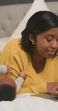 Genç bir anne dizüstü bilgisayarı üzerinde çalışırken bebeğiyle birlikte bir yatakta yatıyor. İş ve aile hayatını dengeliyor, modern bir ebeveynlik tarzı sergiliyor. Sahne sıcaklığı, aşkı ve çoklu görevin zorluklarını çağrıştırıyor..