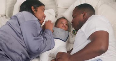 Mutlu bir aile yatakta birlikte zaman geçirmekten hoşlanır. Annem ve babam yanında yatarken bebek ellerini ve ayaklarını nazikçe tutuyorlar. Onu sevgiye boğuyorlar, aile bağlarının iç açıcı bir sahnesini yaratıyorlar..