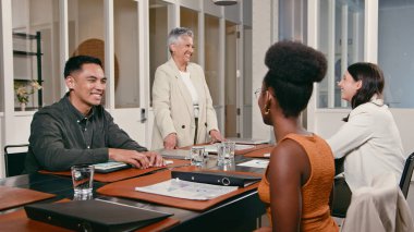 Çeşitli meslektaşlar bir iş toplantısı için profesyonel bir ortamda toplanıyor. Fikirlerini paylaşıyorlar, gülümsüyorlar ve modern ofis ortamında işbirliği yapıyorlar, takım çalışmasını ve üretkenliği teşvik ediyorlar..