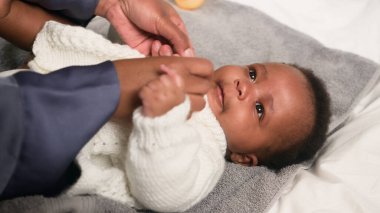 Sevecen bir ebeveyn bebeğini nazikçe giydirir, sevgiyi ve ilgiyi vurgular. Sıcak atmosfer ebeveyn ve çocuk arasındaki bağı vurgular, aile bakımında sıcak ve samimi bir anı yakalar..