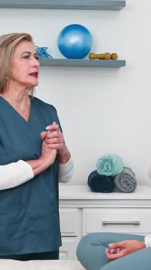 Üst düzey bir kadın fizyoterapist, profesyonel bir konsültasyon sırasında hastasına detaylı bir açıklama sunar. Bu sağlık hizmetleri, iyileşme ve refah için kişisel bakım ve etkili fizik tedaviyi ön plana çıkarmaktadır..