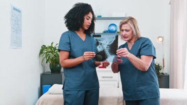 Deneyimli bir fizyoterapist spor bilimi kliniğinde röntgenleri inceleyen genç bir kadına akıl hocalığı yapıyor. Bu etkileşim, gelişmekte olan küçük işletme ortamında profesyonel gelişimi, çeşitliliği ve işbirlikçi hasta bakımını göstermektedir..