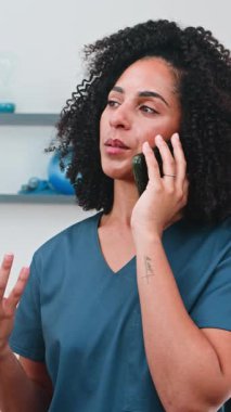 Gülümseyen ve telefonla meşgul olan çeşitli kadın fizyoterapist spor bilimi uygulamasına bağlılığını gösteriyor. Profesyonel iletişim yoluyla hastanın refahını sağlamak için şefkatli bakım ve uzman tıbbi tavsiyeler sunuyor..