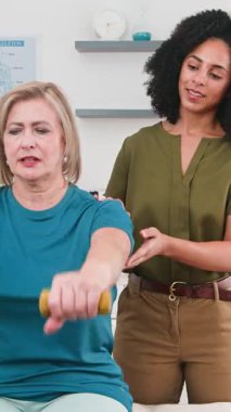 Profesyonel siyahi kadın fizyoterapist kıdemli bir hastaya rehabilitasyon egzersizlerinde rehberlik ediyor, halterle güç ve iyileşme üzerine odaklanıyor. Daha iyi sağlık ve sağlık için aktif yaşlanma ve gelişmiş fonksiyonel hareketi vurgulamak.