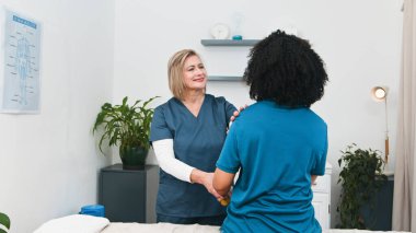 Yetenekli bir kıdemli fizyoterapist genç siyah bir müşteriye hareket değerlendirmesi ve tedavi uygular. Profesyonel fizyoterapi, sporcular ve aktif bireyler için ağrı kesici ve daha iyi hareket kabiliyeti sunar..