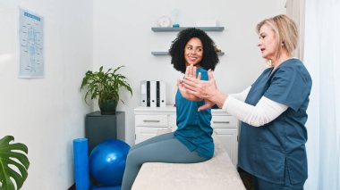 Yetenekli bir kıdemli fizyoterapist genç siyah bir müşteriye hareket değerlendirmesi ve tedavi uygular. Profesyonel fizyoterapi, sporcular ve aktif bireyler için ağrı kesici ve hareket kabiliyetinin geliştirilmesini sunar..