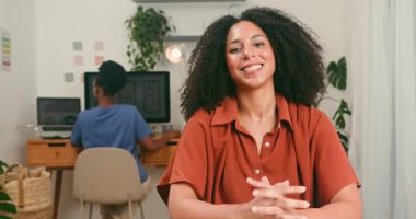 Meslektaşı modern bir teknoloji şirketinde bilgisayar üzerinde çalışırken kendine güvenen farklı bir kadın doğrudan kameraya gülümsüyor. İnovasyon, işbirliği ve genç girişimciler için olumlu bir profesyonel ortam.