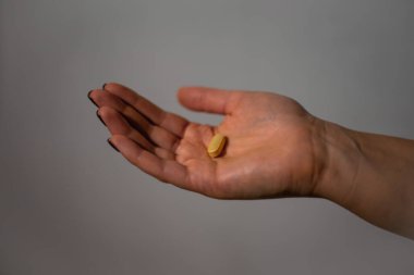 Gri arka planda takviyeleri tutan el. Yüksek kalite fotoğraf