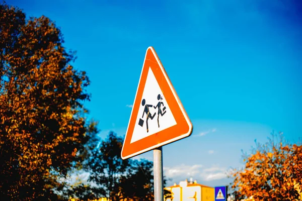 Road sign caution children over blue sky background and tree. High quality photo