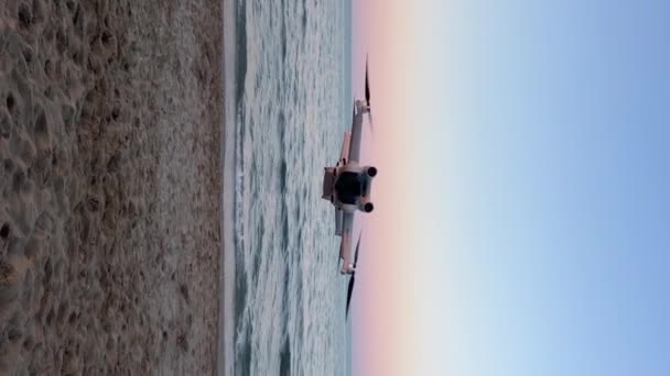 イタリア リミニ20 2023 Dji Mini Proドローンは美しい日没で海岸に飛びます イタリアのアドリア海の背景に浮かぶ新しいクワッドコプター装置 垂直ビデオドローン — ストック動画