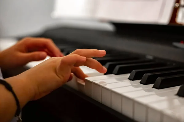 Piyano çalan kız, yakın çekimde piyano, beyaz ve siyah klavye. Yakın plan portre kızı oturma odasında elektronik bir sentezleyicinin tuşlarında melodi çalıyor. Yüksek kalite fotoğraf