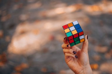 Italia, Milano 15.11.2023: elinde bir Rubik küp tutan kız. İş kadını bir bulmacaya çözüm arıyor. Rebus, yap-boz. Yaratıcı fikirler ortaya atıldı. Yüksek kalite fotoğraf.