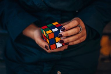 Italia, Milano 15.11.2023: elinde bir Rubik küp tutan kız. İş kadını bir bulmacaya çözüm arıyor. Rebus, yap-boz. Yaratıcı fikirler ortaya atıldı. Yüksek kalite fotoğraf.