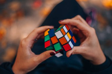 Italia, Milano 15.11.2023: elinde bir Rubik küp tutan kız. İş kadını bir bulmacaya çözüm arıyor. Rebus, yap-boz. Yaratıcı fikirler ortaya atıldı. Yüksek kalite fotoğraf.