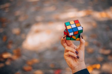 Italia, Milano 15.11.2023: elinde bir Rubik küp tutan kız. İş kadını bir bulmacaya çözüm arıyor. Rebus, yap-boz. Yaratıcı fikirler ortaya atıldı. Yüksek kalite fotoğraf.