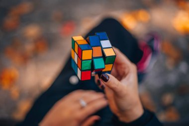 Italia, Milano 15.11.2023: elinde bir Rubik küp tutan kız. İş kadını bir bulmacaya çözüm arıyor. Rebus, yap-boz. Yaratıcı fikirler ortaya atıldı. Yüksek kalite fotoğraf.